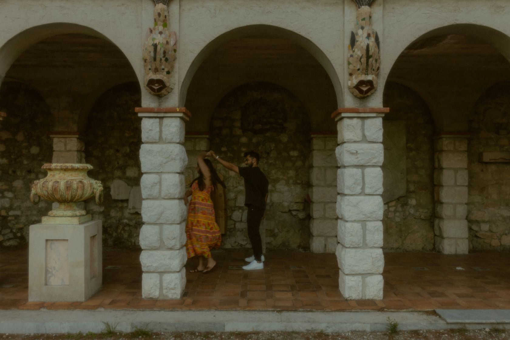 Image d'un couple devant des colonnes de pierre, l'homme fait danser la femme en la faisant tourner